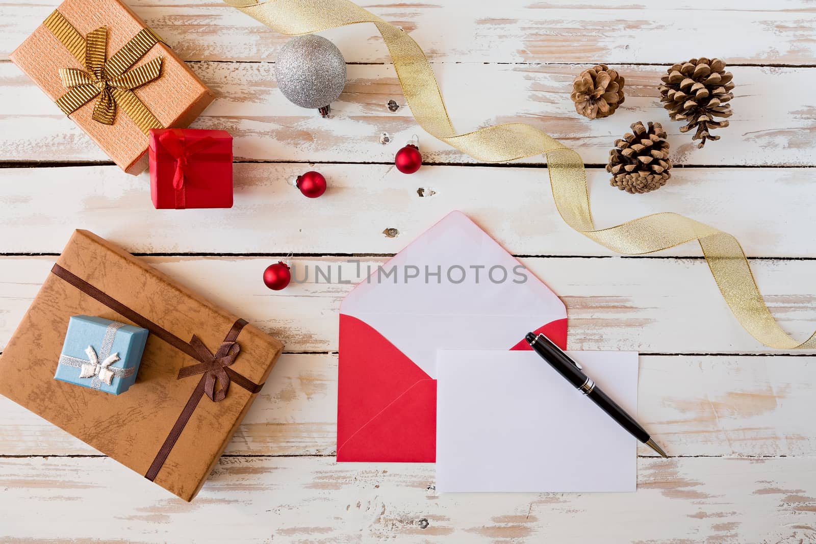 Christmas letter and pen over a rustic wooden table with presents, decorations and pine cones
