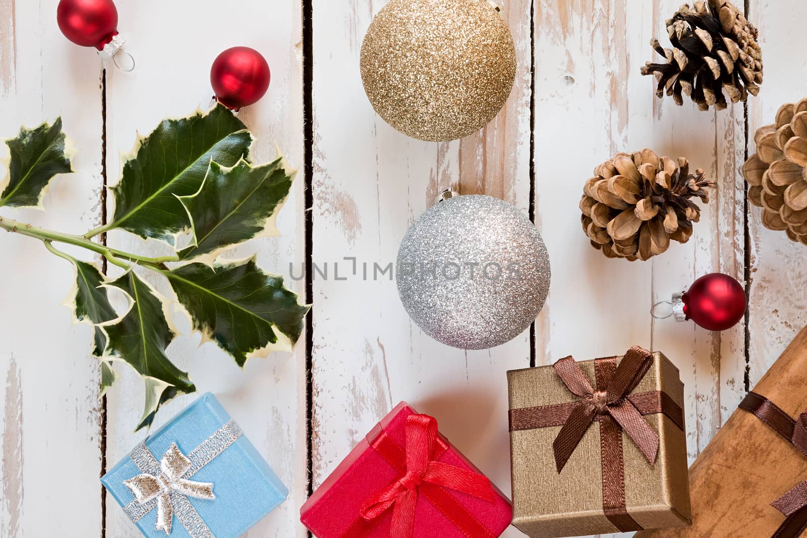 Closeup of Christmas presents and decorations over a rustic wooden table seen from above