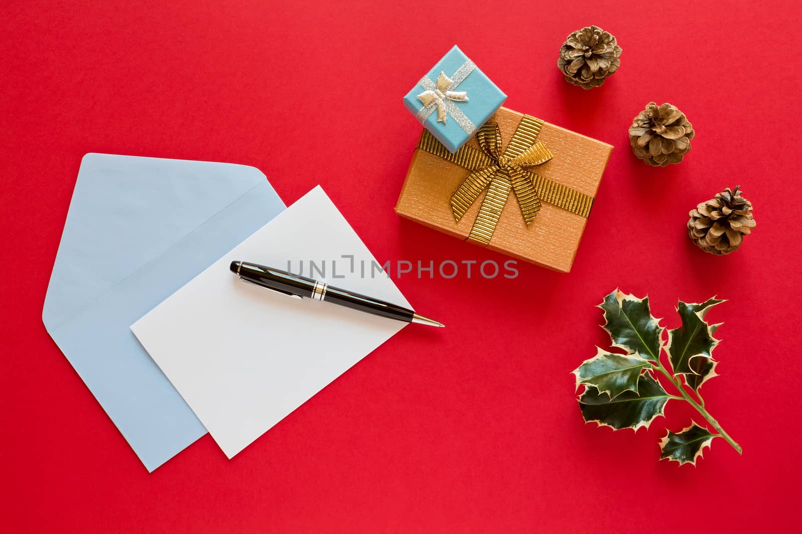Christmas letter and pen over a red background with presents and pine cones