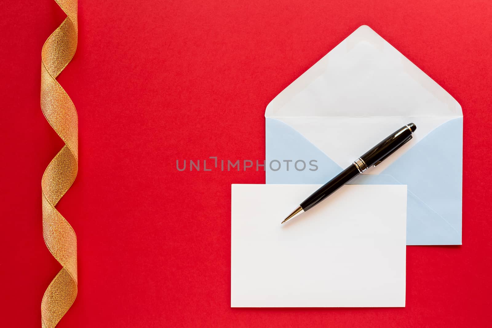 Christmas letter and pen over a red background with golden ribbon