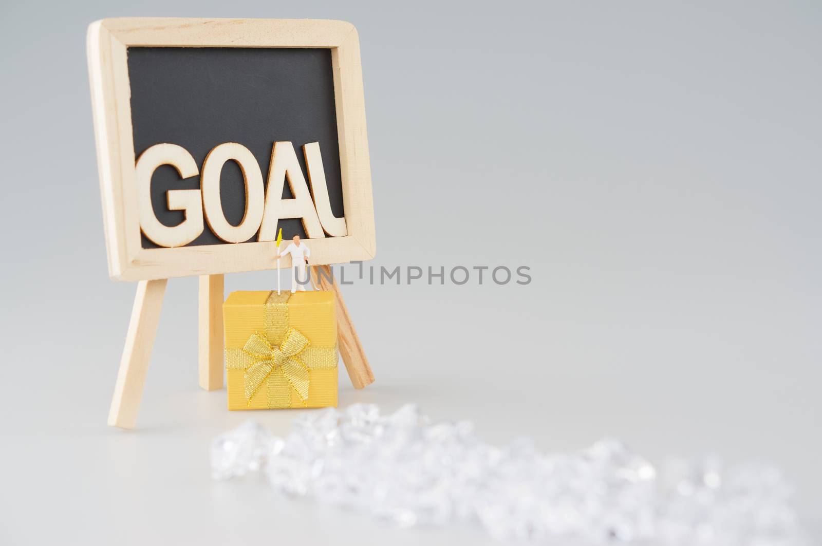 Man effort to work hard hold flag and golf club for successful in goal. Man is walking from left to right of blackboard and jumping to gold gift box. Business success concept photography.
