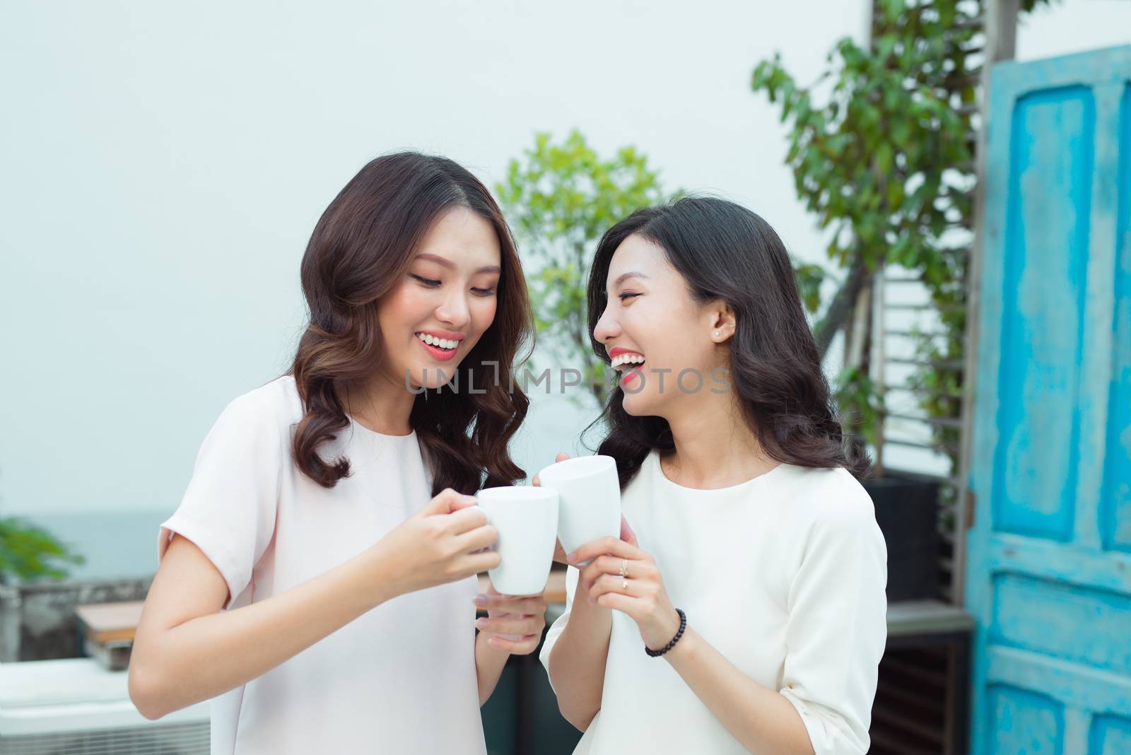 Beautiful asian woman friends holding plastic cup of ice black coffee on balcony 