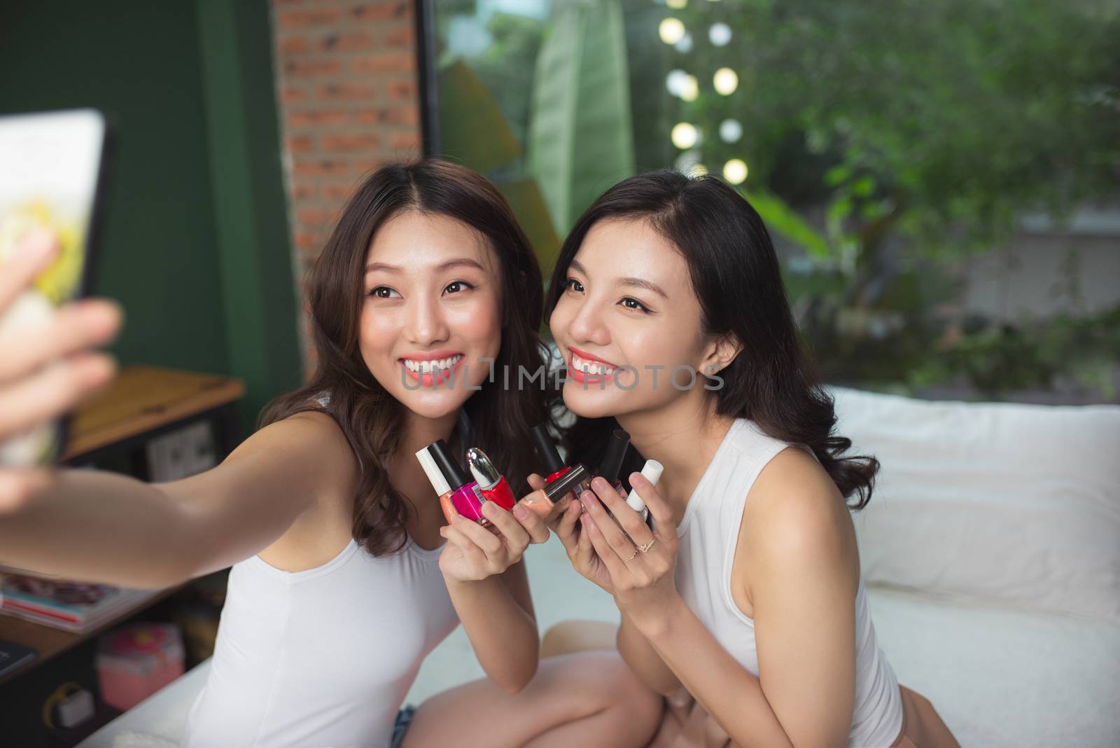 Two asian women in the bedroom on the bed  paint their nails and by makidotvn