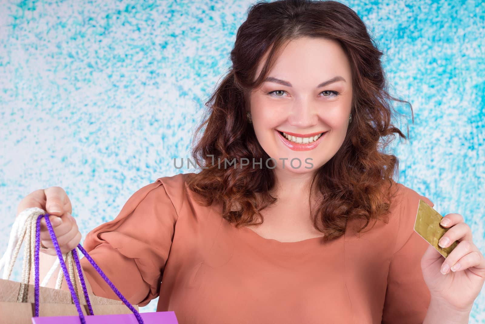 Happy smiling woman holding colourful shopping paper bags and banking credit card
