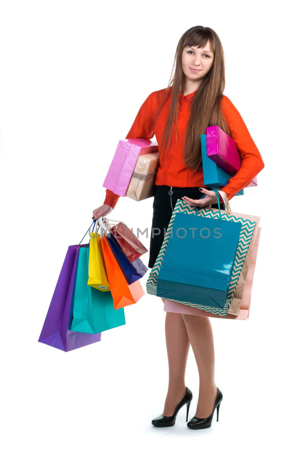 Young long-haired woman stands with many colorful paper packages and boxes in her arms after shopping