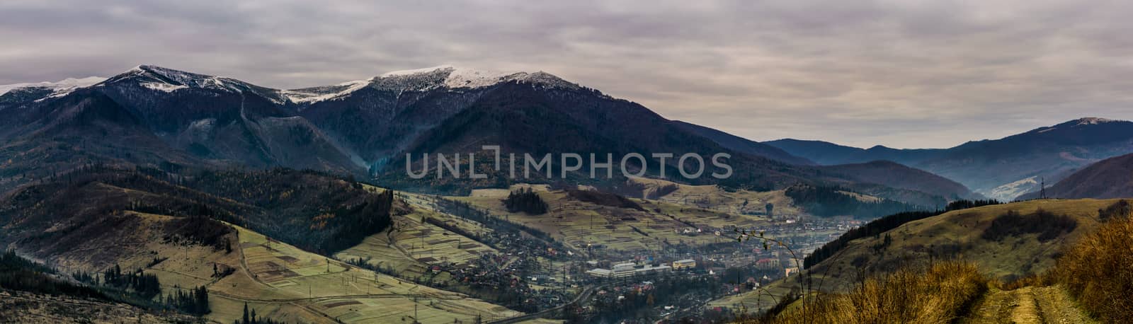 panorama of mountainous countryside in late autumn. great Borzhava mountain ridge with snowy tops and villge down the valley at sunrise