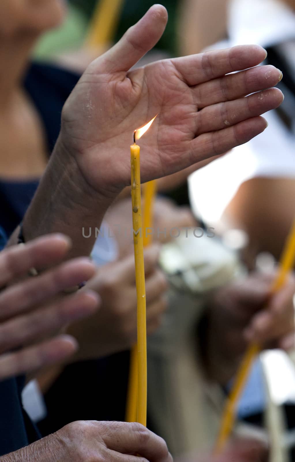 A hand shields a candle during a religious ceremony.