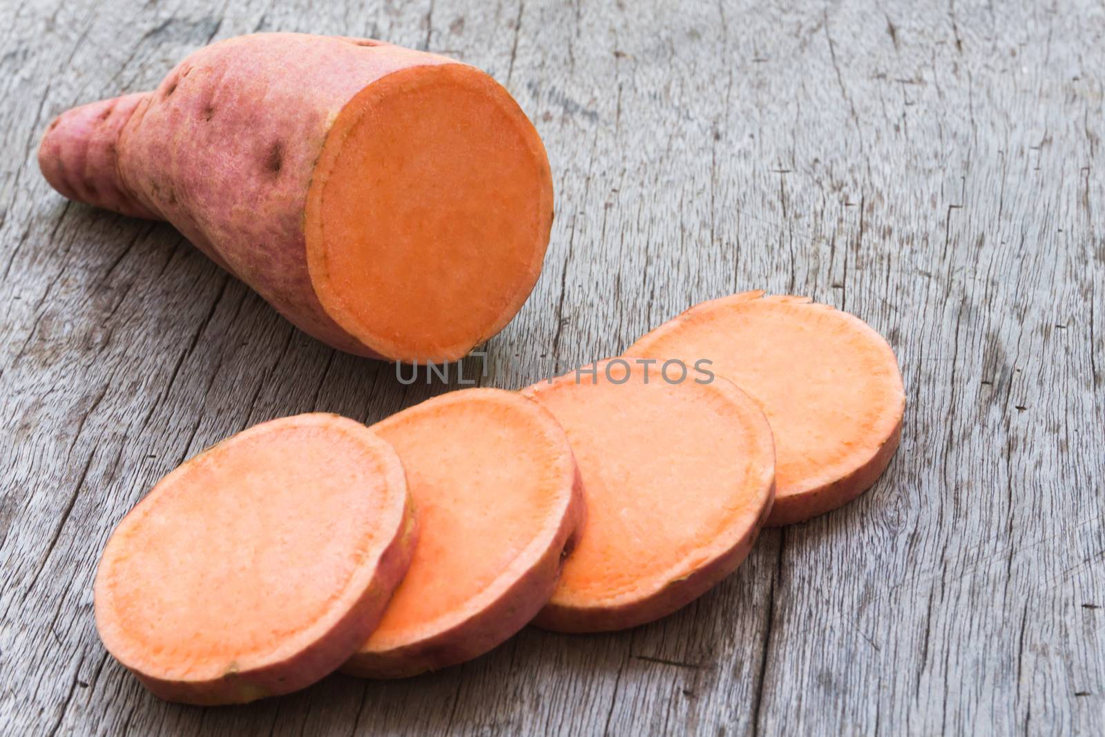 Sweet potato with slices on wooden background, raw food