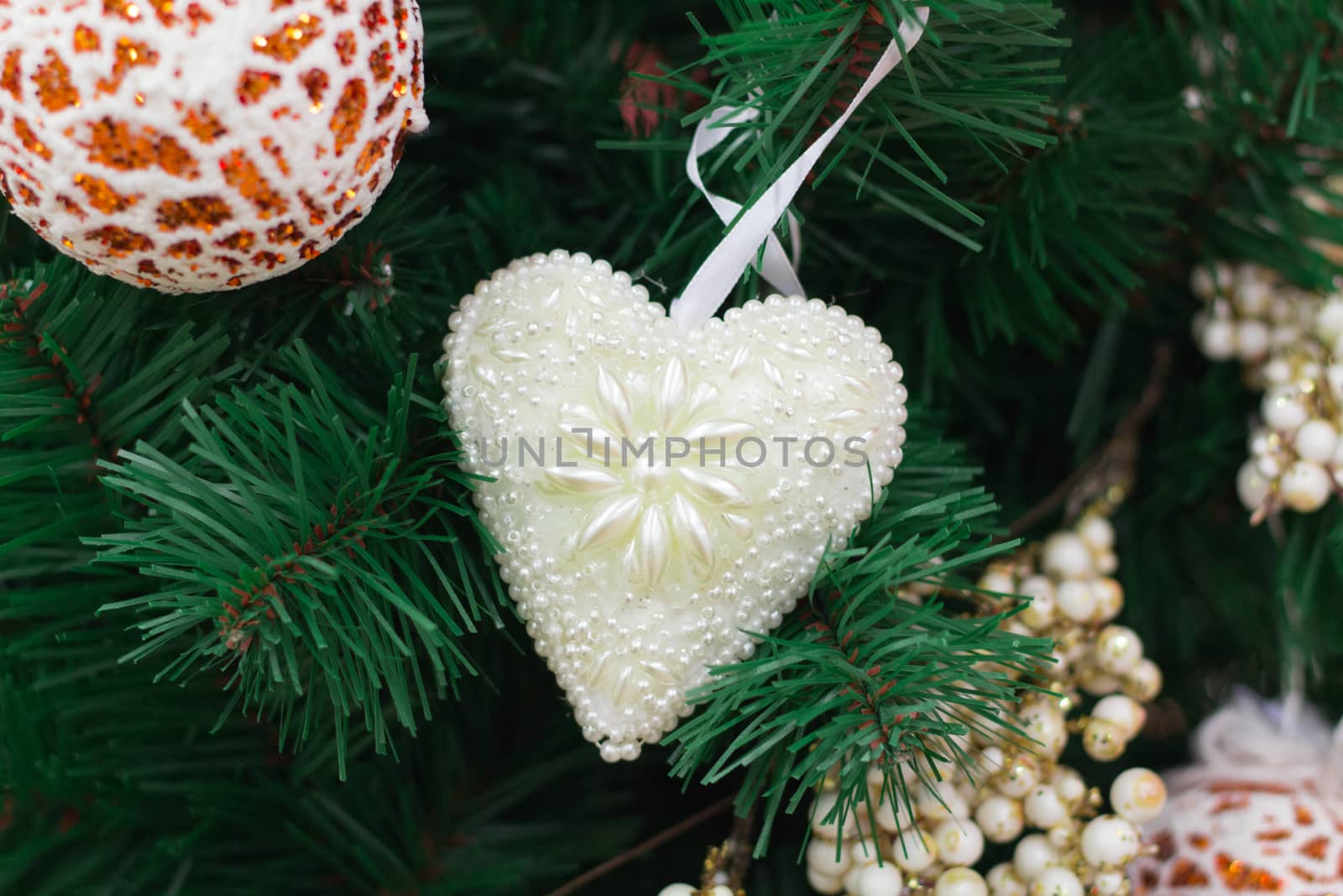 Christmas and New Year seasonal decoration, green tree branches with orange ball and white heart ornaments