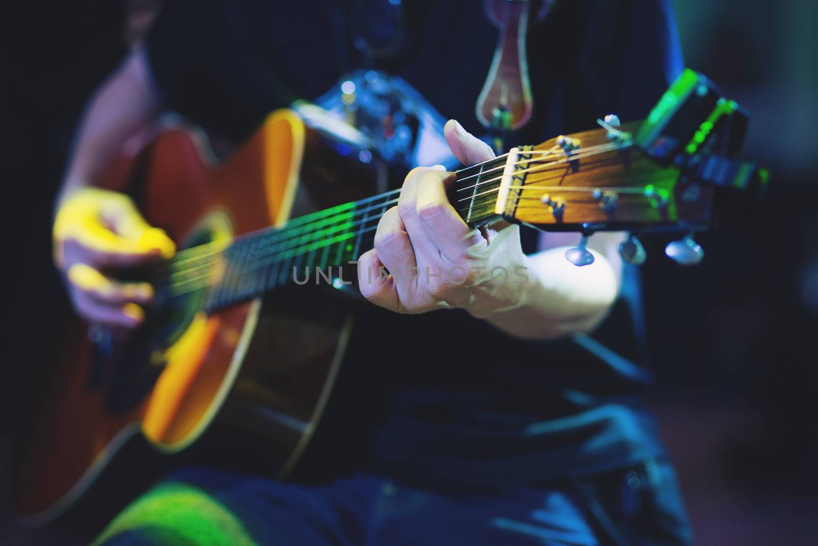 Acoustic guitar guitarist playing. Musical instrument with performer hands on stage in Concert