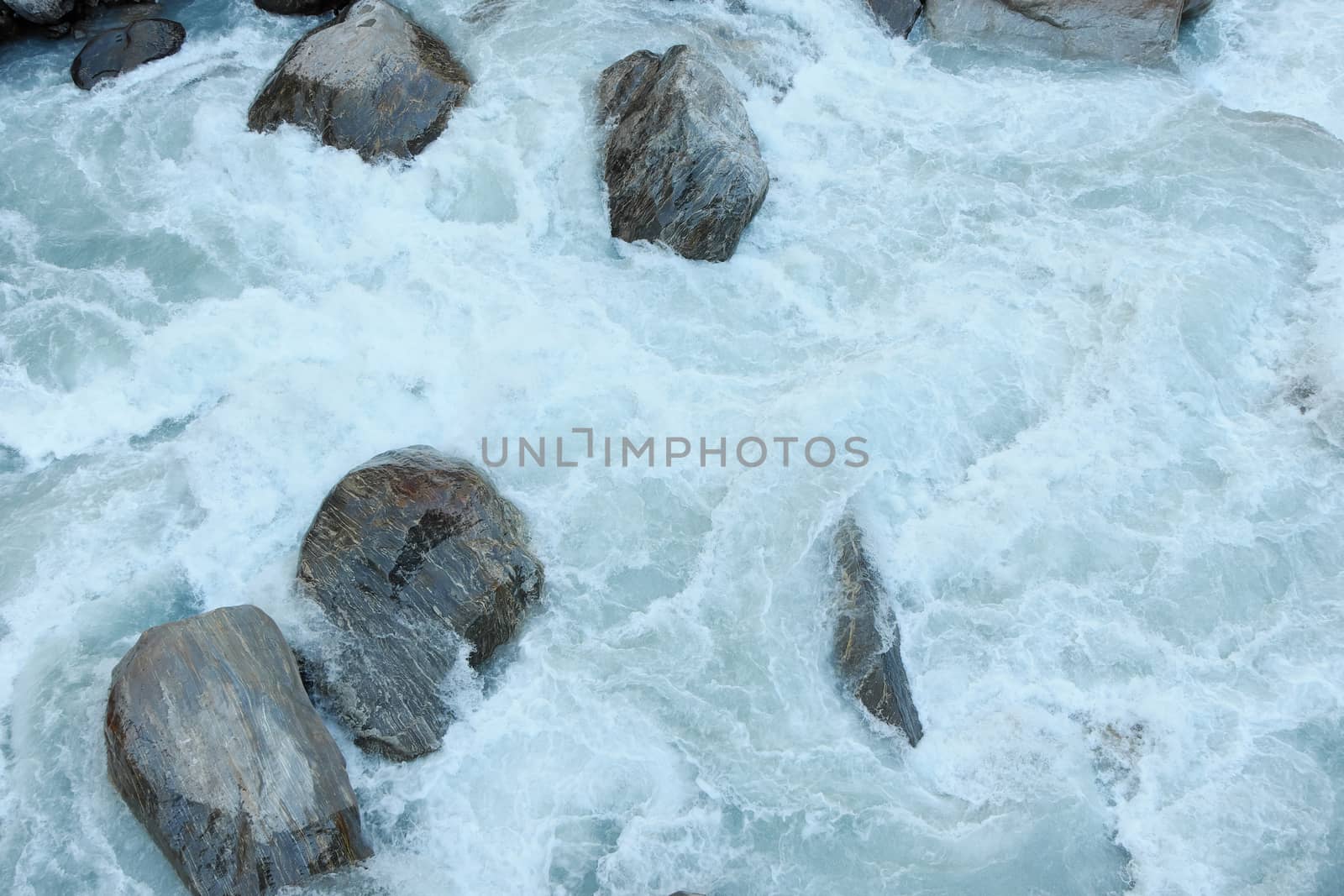 Stormy flow of white water in a mountain river among large boulders 