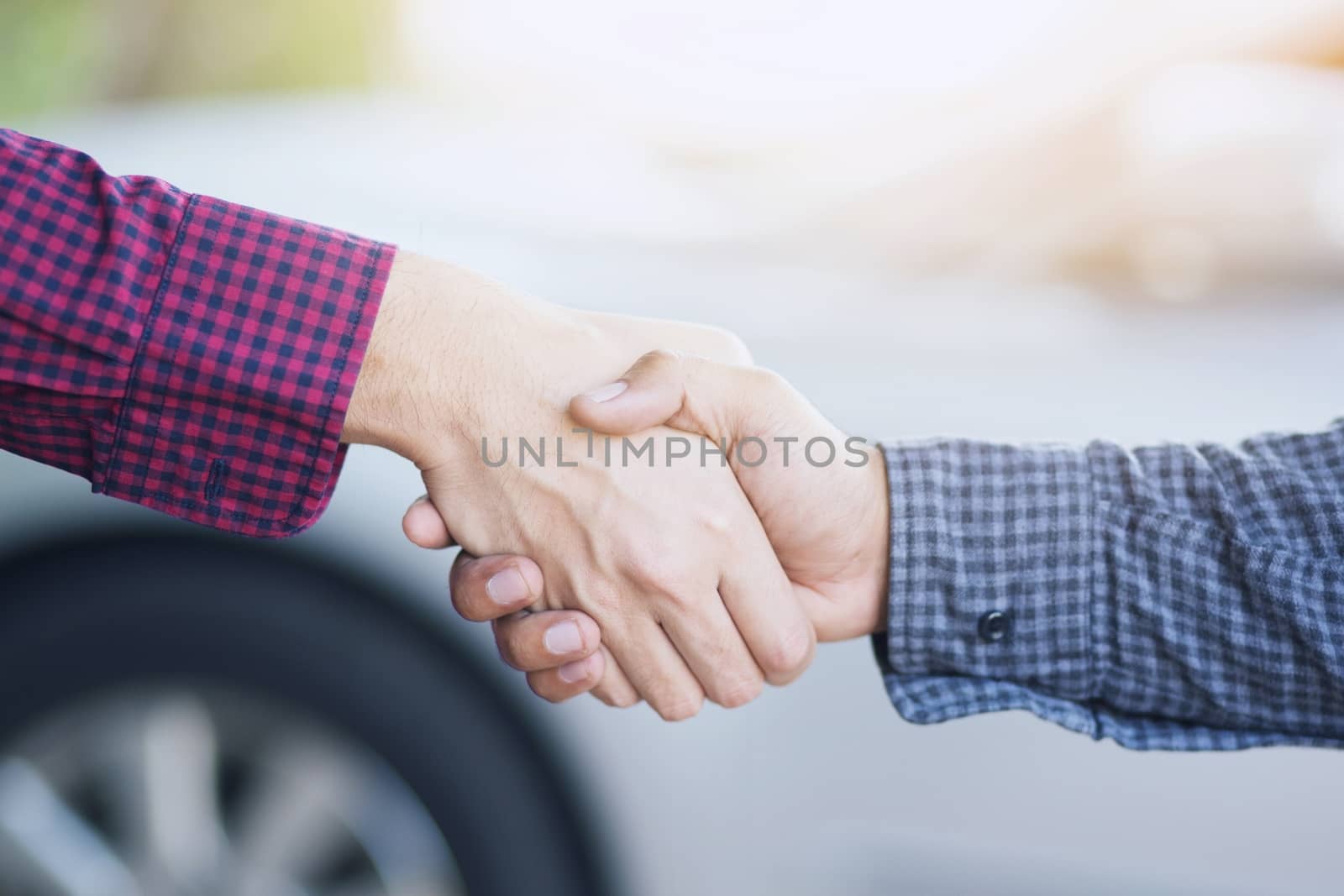 Closeup of a business hand shake between two colleagues Plaid shirt. or Car sales success. by boytaro1428@gmail.com