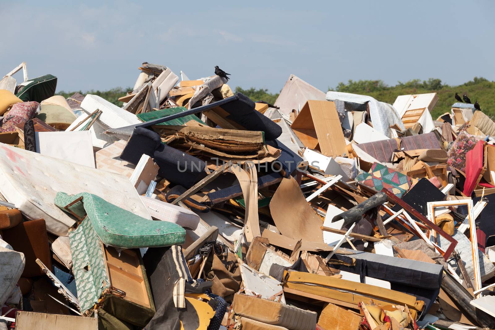 Old furniture at the garbage dump in focus, nature and blue sky in the background