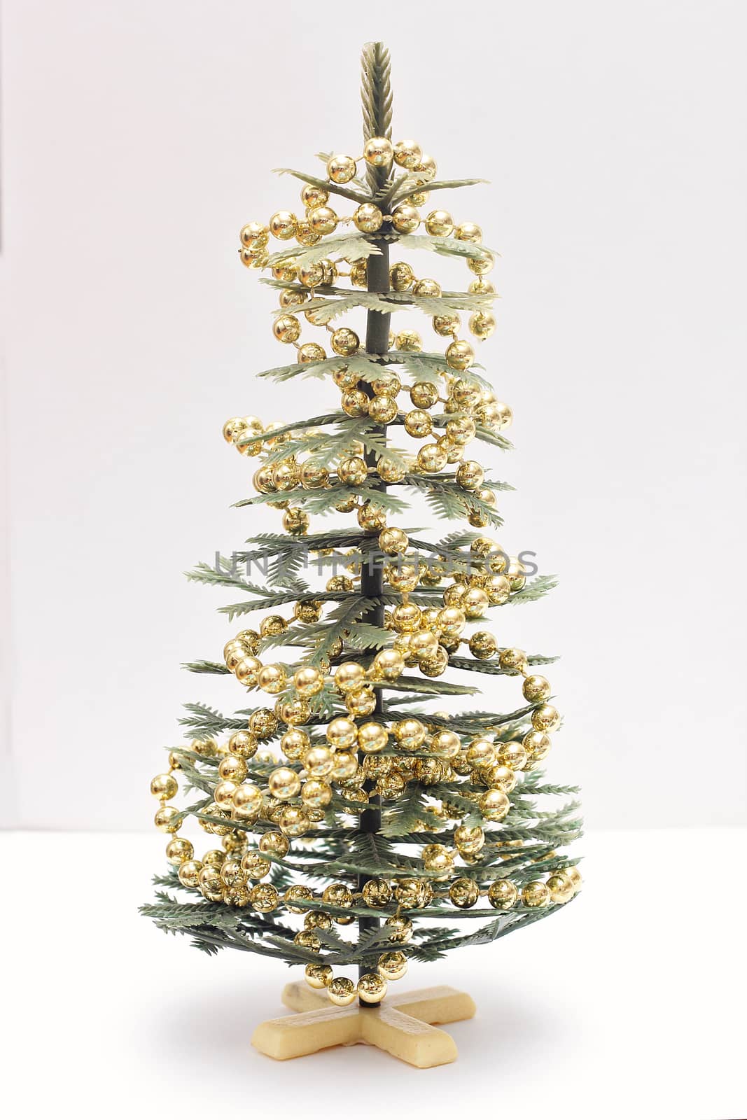 A small artificial Christmas tree decorated with decorative beads on a white background.