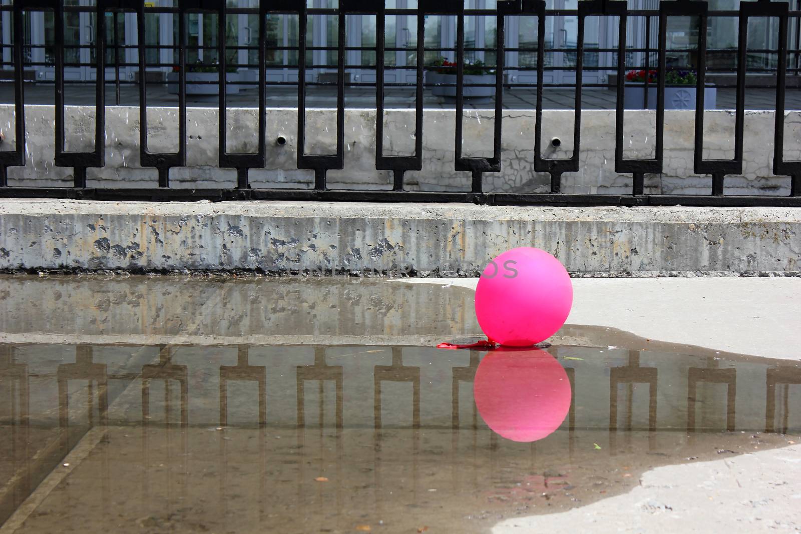 Pink ball on the concrete embankment with a metal fencing