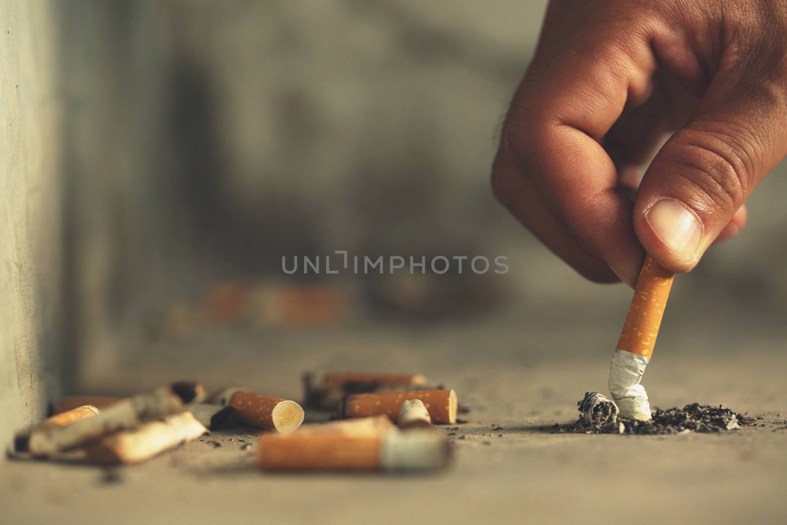 Hand putting out a cigarette,cigarette butt on Concrete floor, bare cement. by boytaro1428@gmail.com