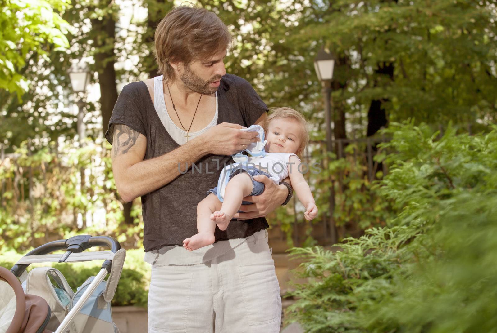 A father is taking care of his baby on a sunny summer day.