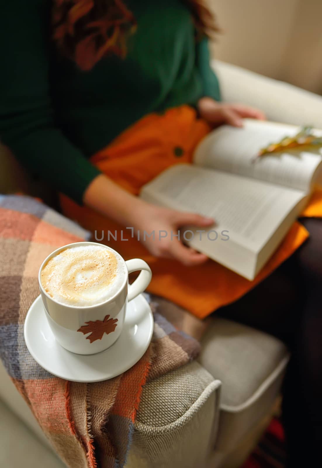 Cup of cappuccino coffee and girl reading a book