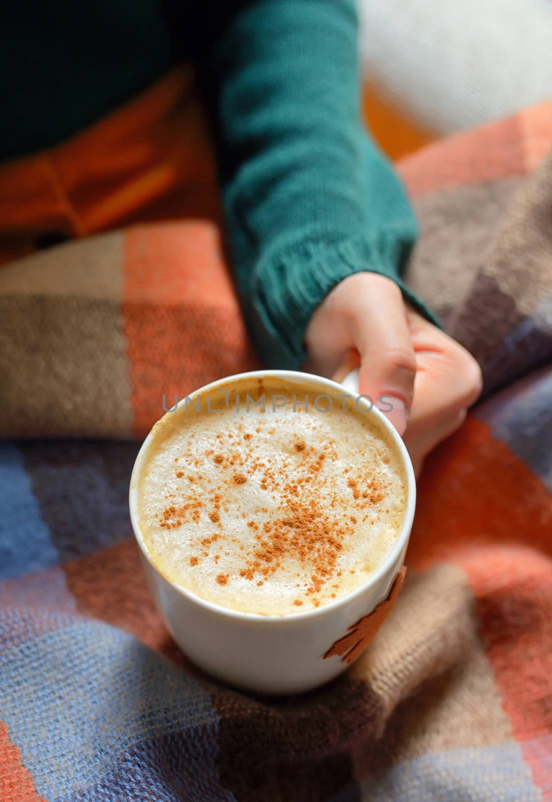 Girl with cup of cappuccino coffee on blanket 