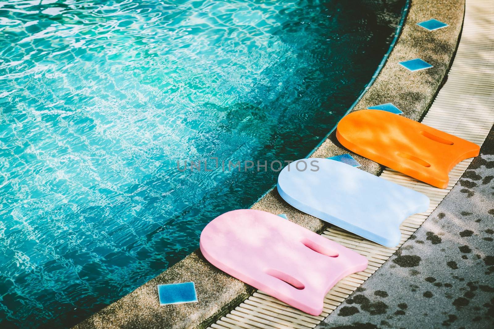 Kickboard equipment provided in a refreshing blue swimming pool.