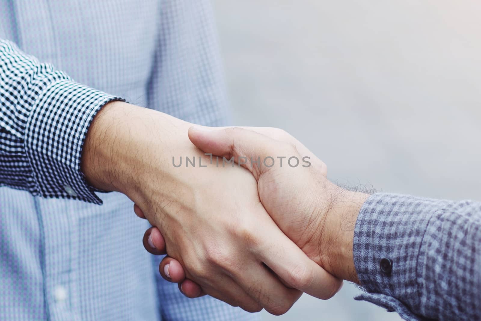 Closeup of a business hand shake between two colleagues Plaid shirt by boytaro1428@gmail.com