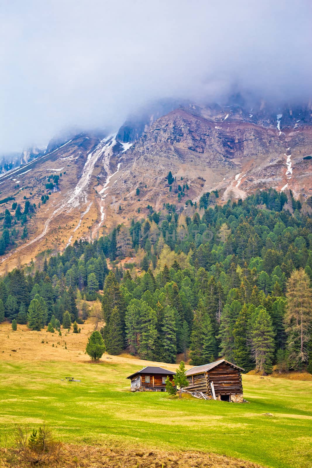 Alpine peak in fog and mountain hut vertical view, Gislergruppe mountains in Alps, South Tyrol, Italy