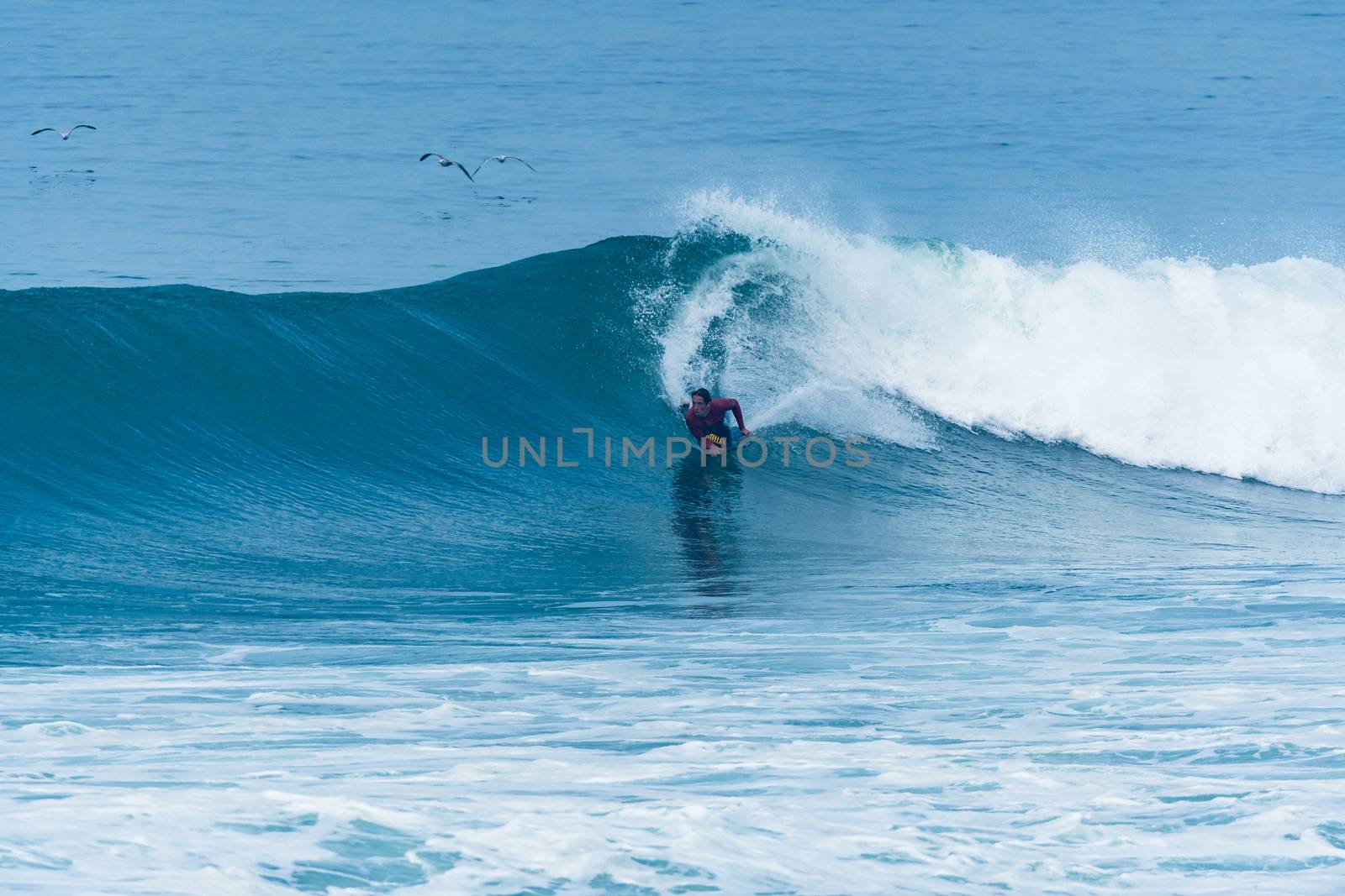 Bodyboarder surfing ocean wave on a sunny day.