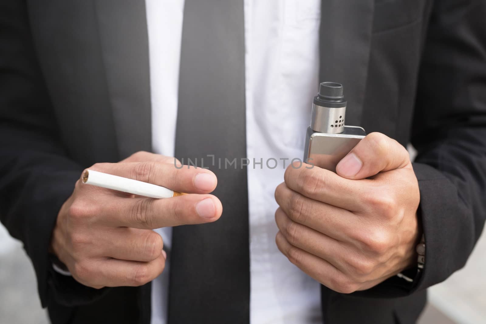 Close-up Of Business man Hold Electronic Cigarette In Hand concept of choosing the type of cigarette. by boytaro1428@gmail.com
