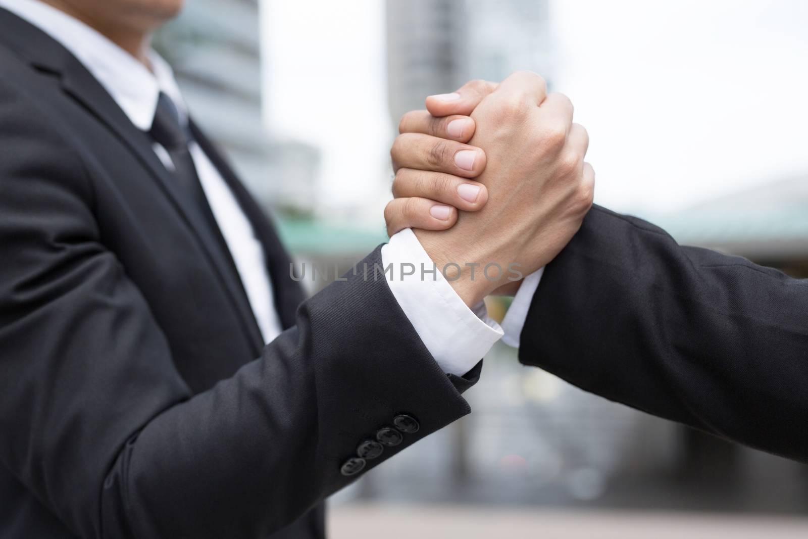 companionship hand clasping success trust, confident concept. or Closeup of a businessman hand between two colleagues on outdoor building.