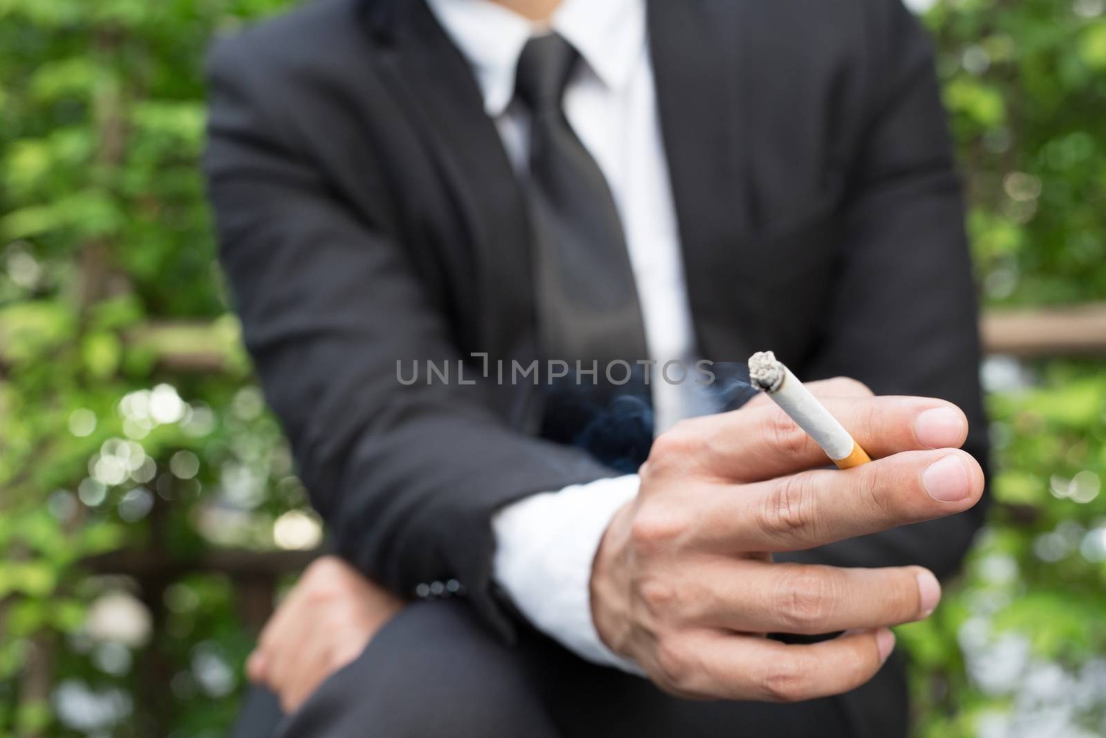 businessmen cigarettes for smoking sit in the park in the smoking zone area.