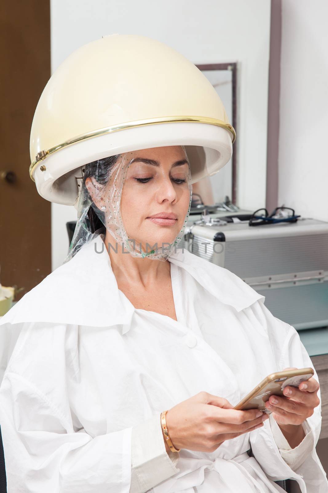 Woman under a professional hair steamer with a hair treatment