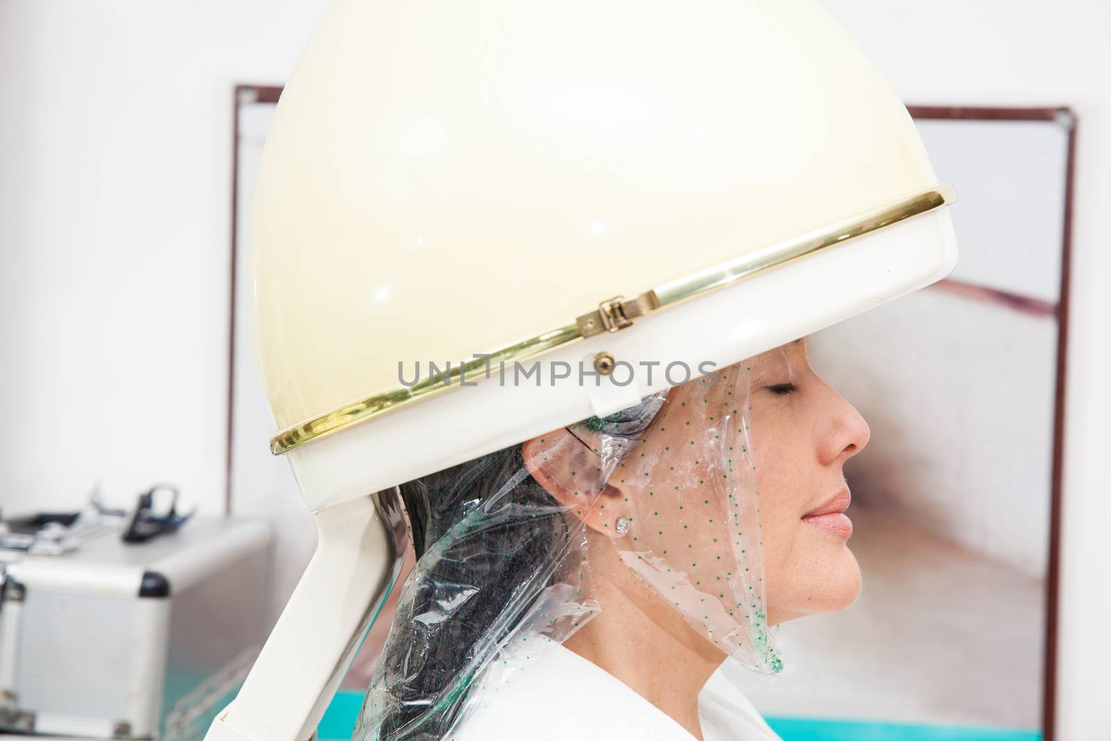 Woman under a professional hair steamer with a hair treatment