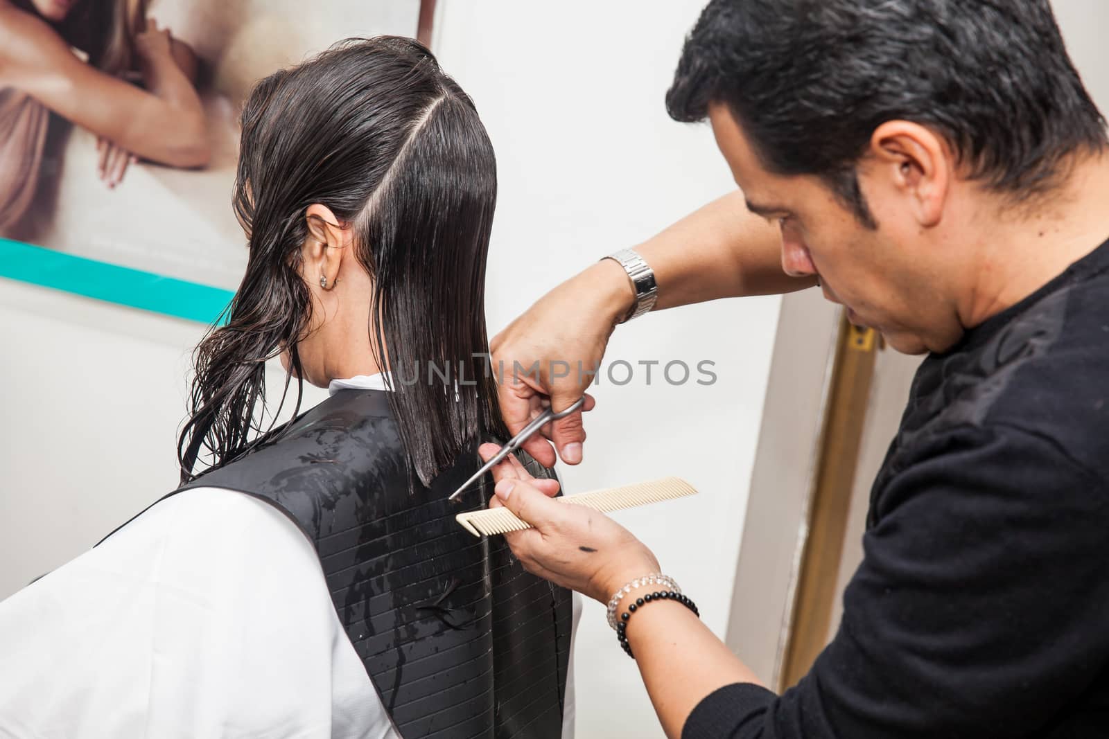 Male stylist making a haircut to a white woman