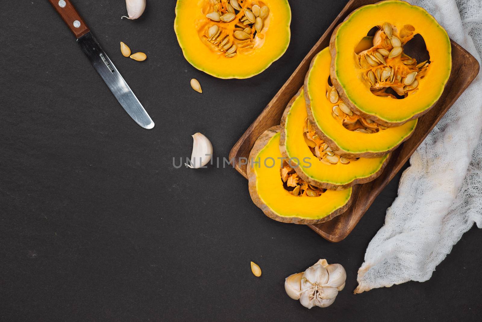 Nutrition concept. Pumpkin slices on black stone background. by makidotvn
