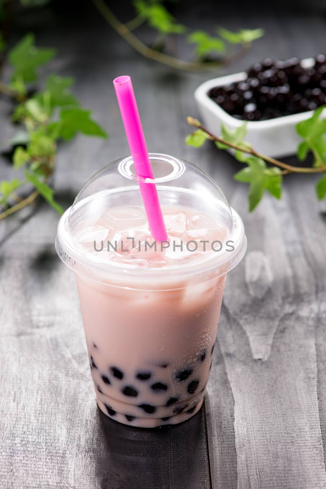 Bubble boba tea with milk and tapioca pearls in plastic cup by makidotvn