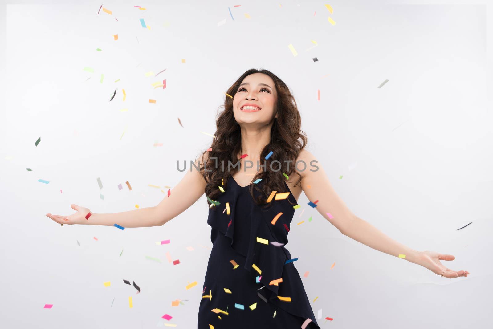 Happy asian woman celebrating with confetti on white background