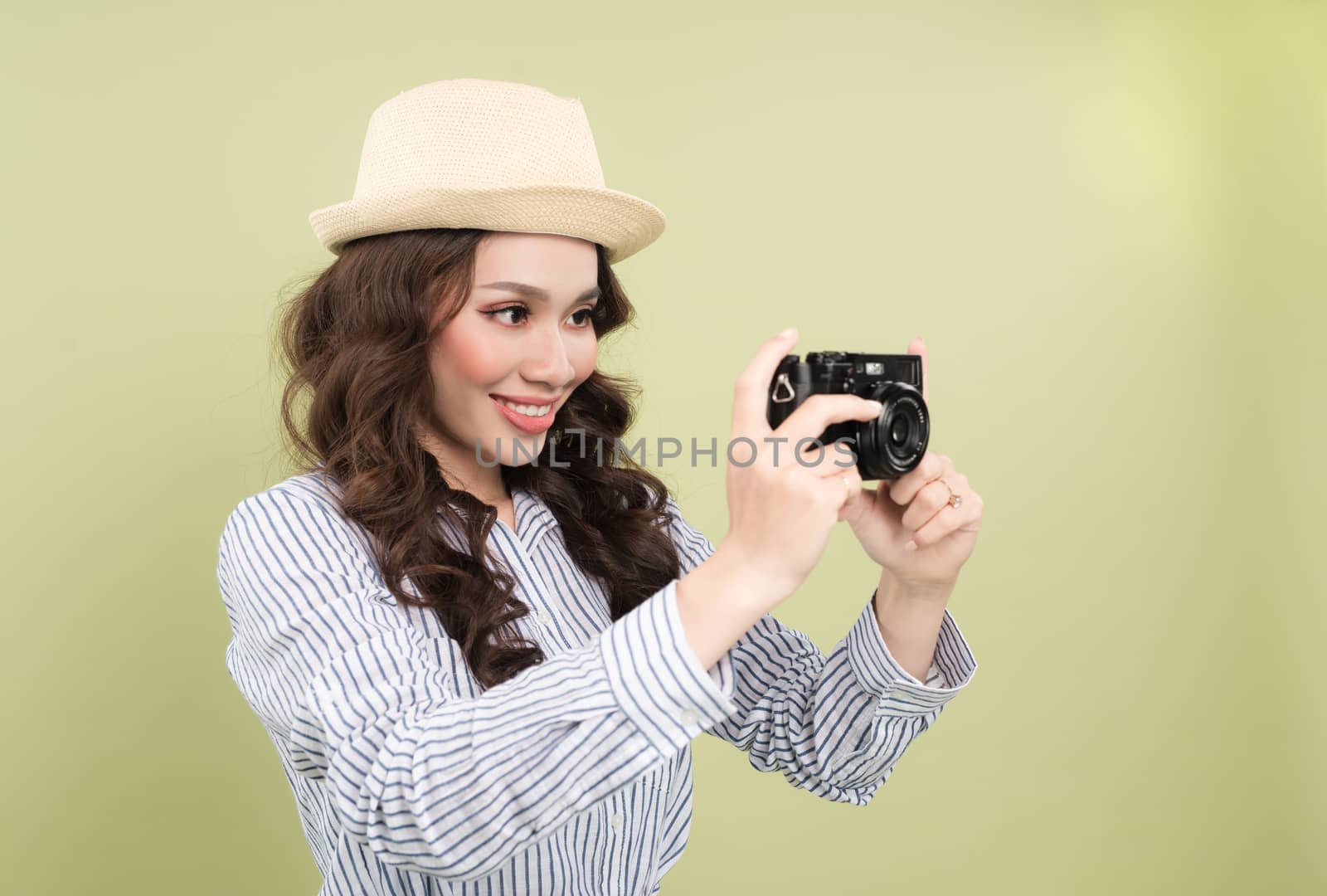 Young beautiful woman with camera on green background