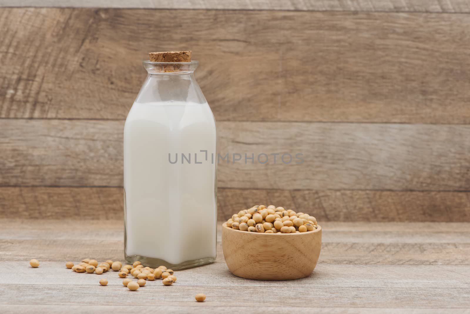 Bottle of soy milk and soybean on wooden table by makidotvn