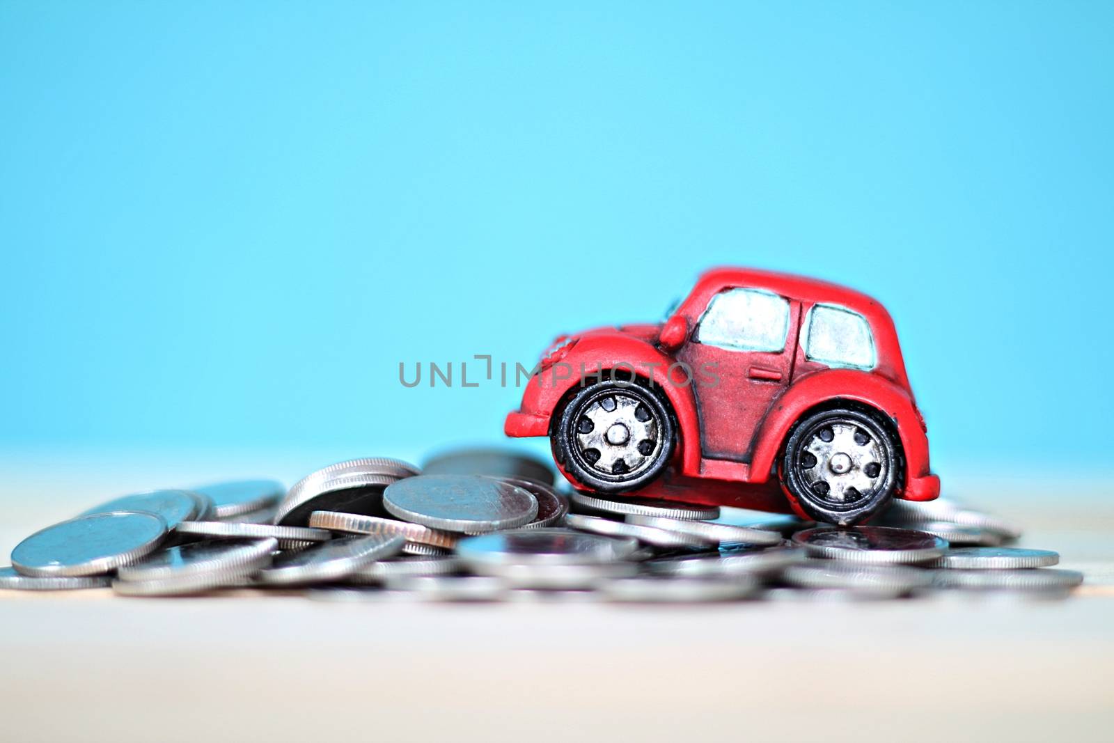 Miniature car model and coins on desk table by sureeporn