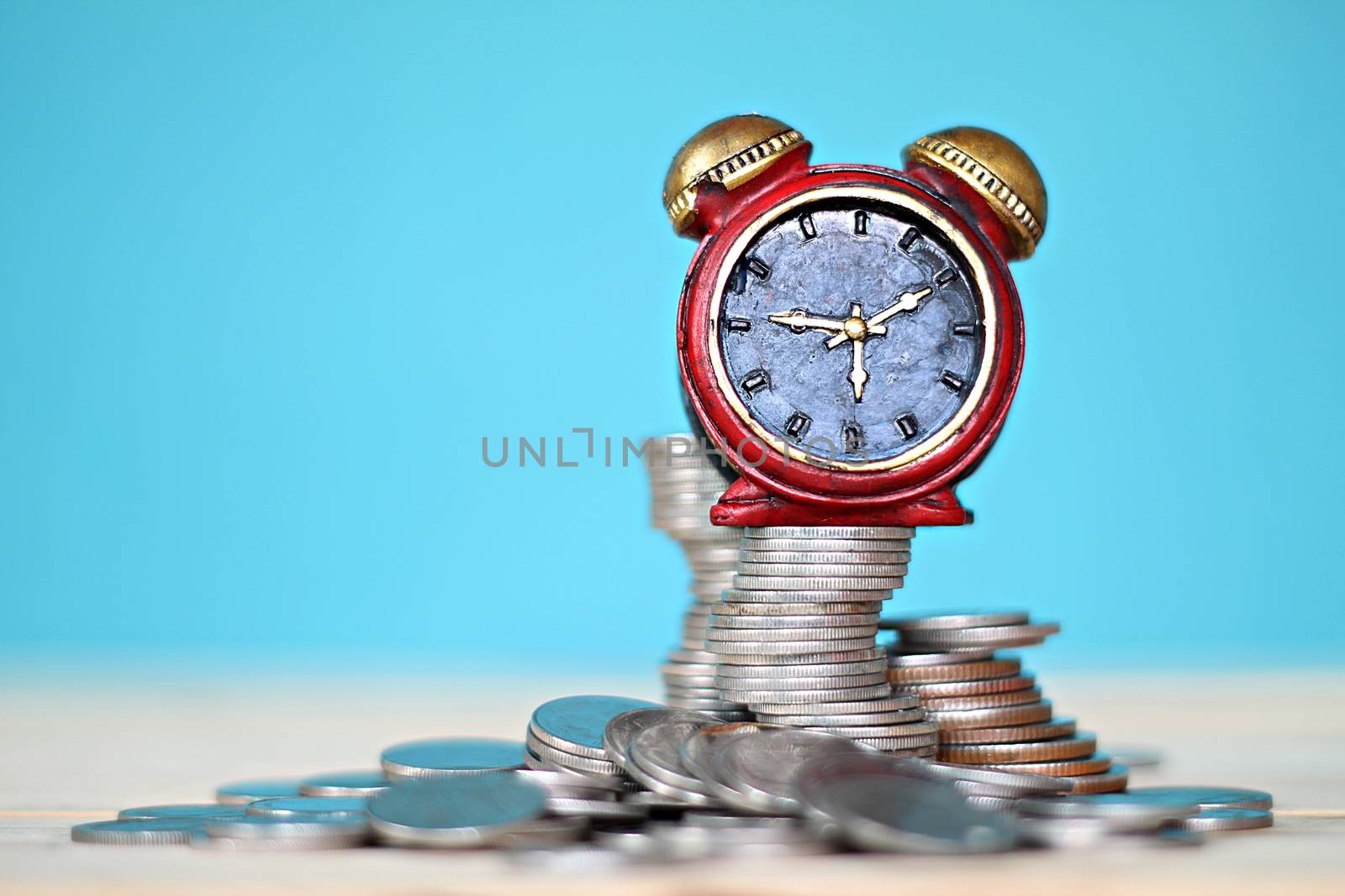 Business, finance, saving money and time concept : Miniature clock and coins stack on desk table