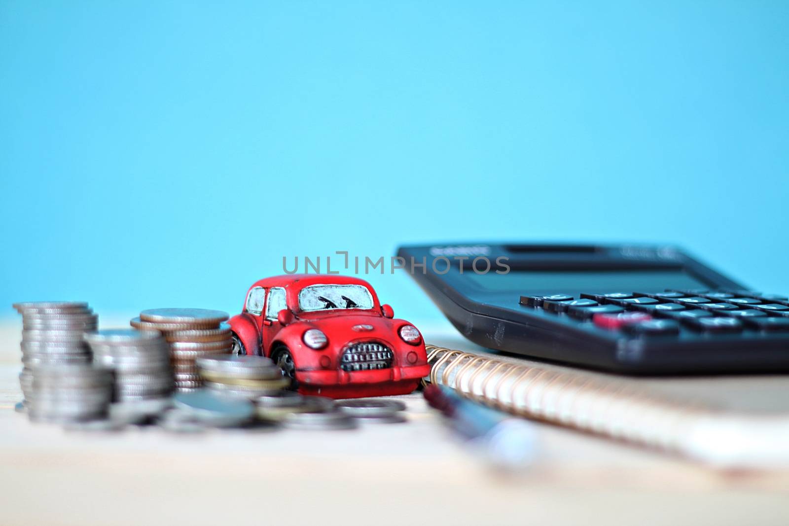 Business, finance, saving money or car loan concept : Miniature car model, coins stack, calculator and notebook paper on office desk table