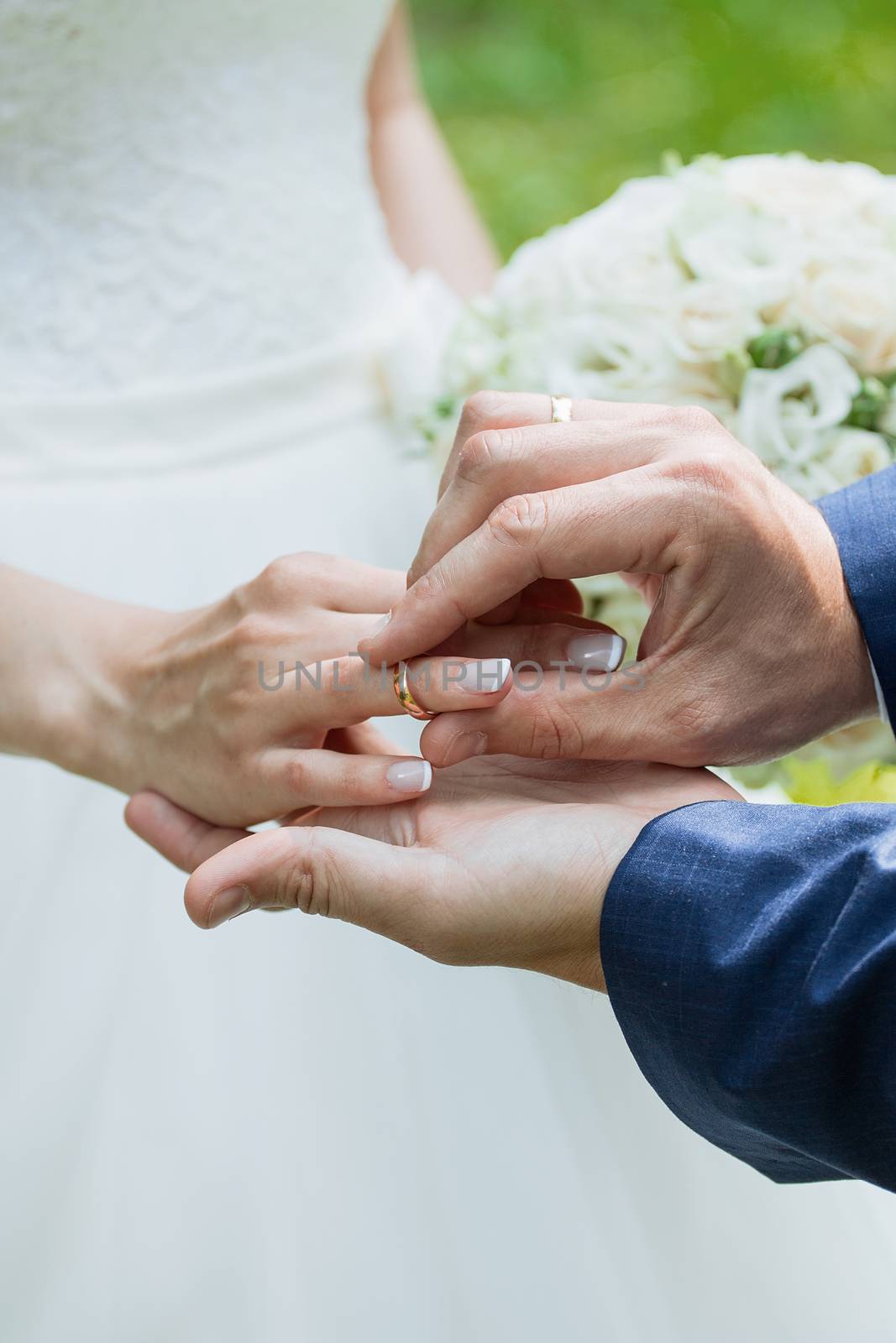 The groom places the ring on the bride's hand. Photo closeup by 3KStudio