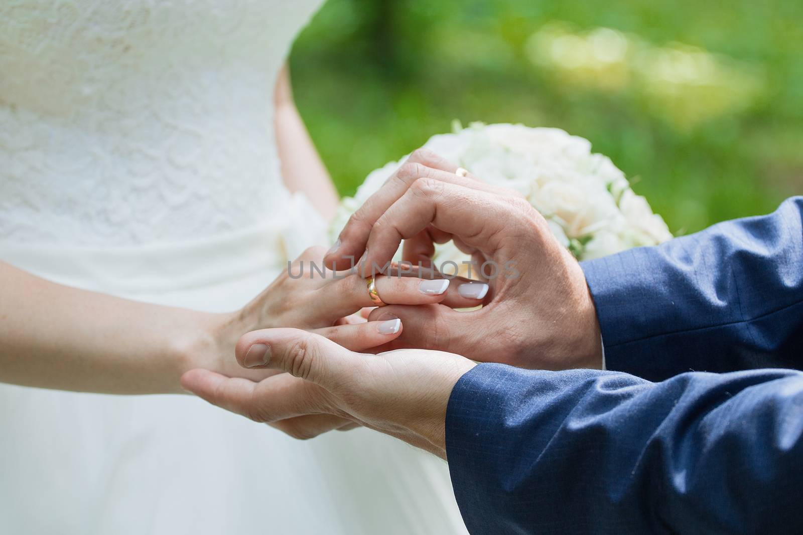 The groom places the ring on the bride's hand. Photo closeup by 3KStudio