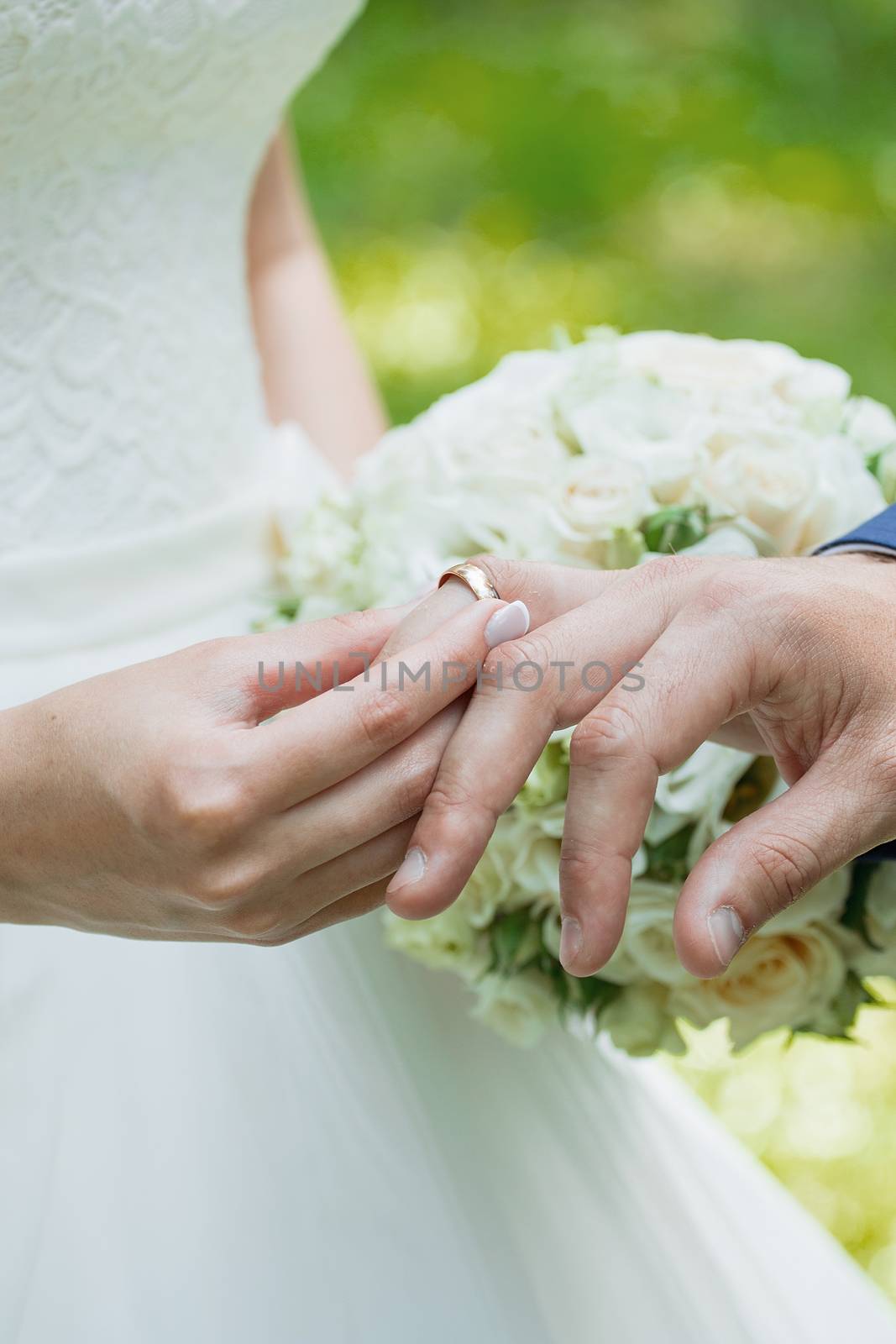 Wedding day. The groom places the ring on the bride's hand.