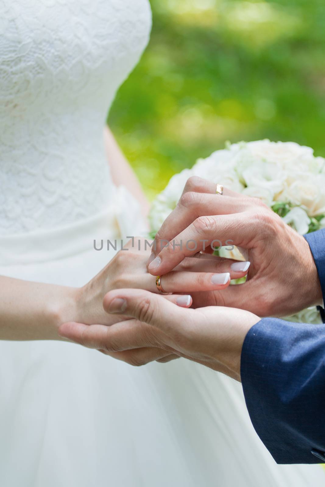 Wedding day. The groom places the ring on the bride's hand.