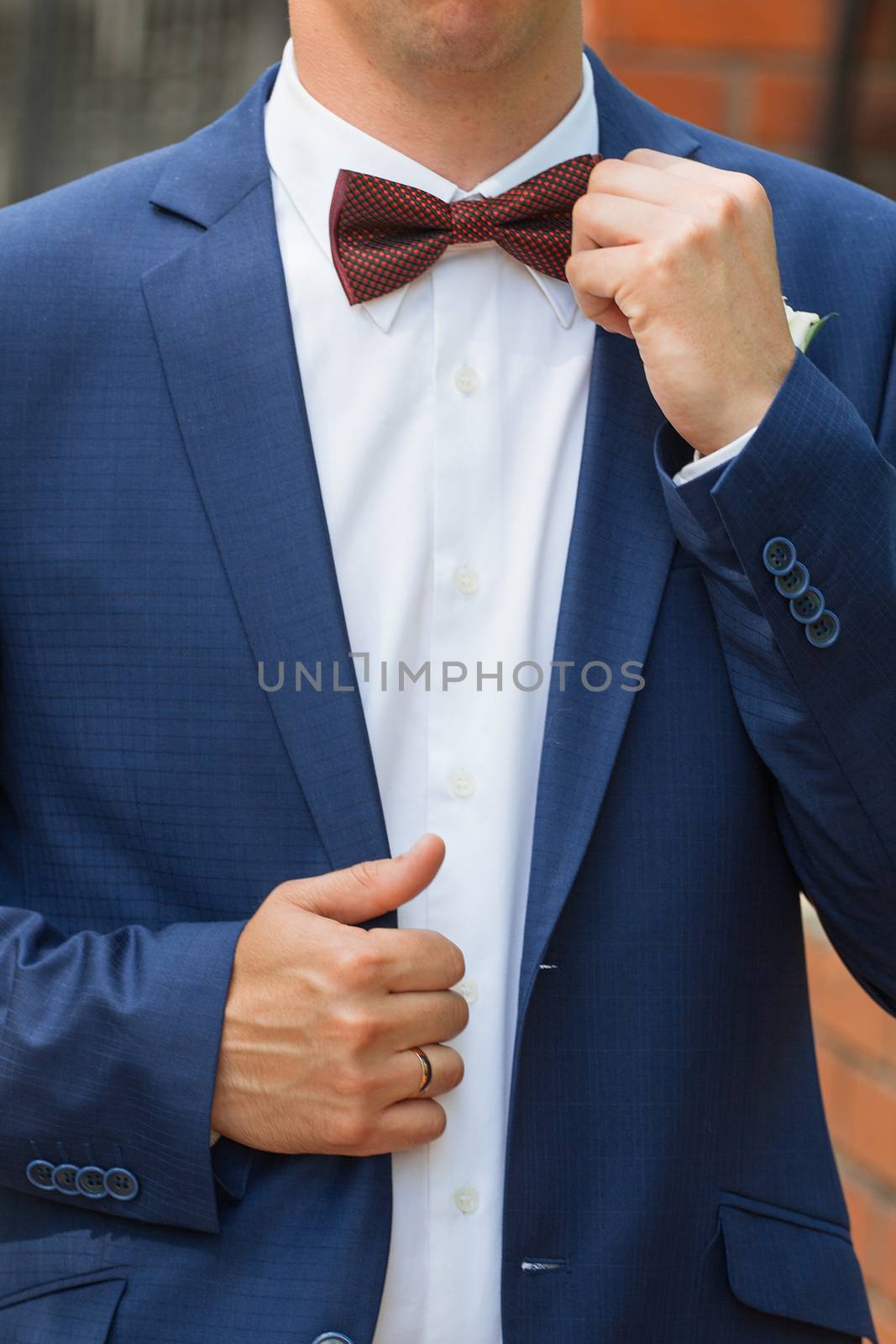 Stylish groom straightens a tie . by 3KStudio