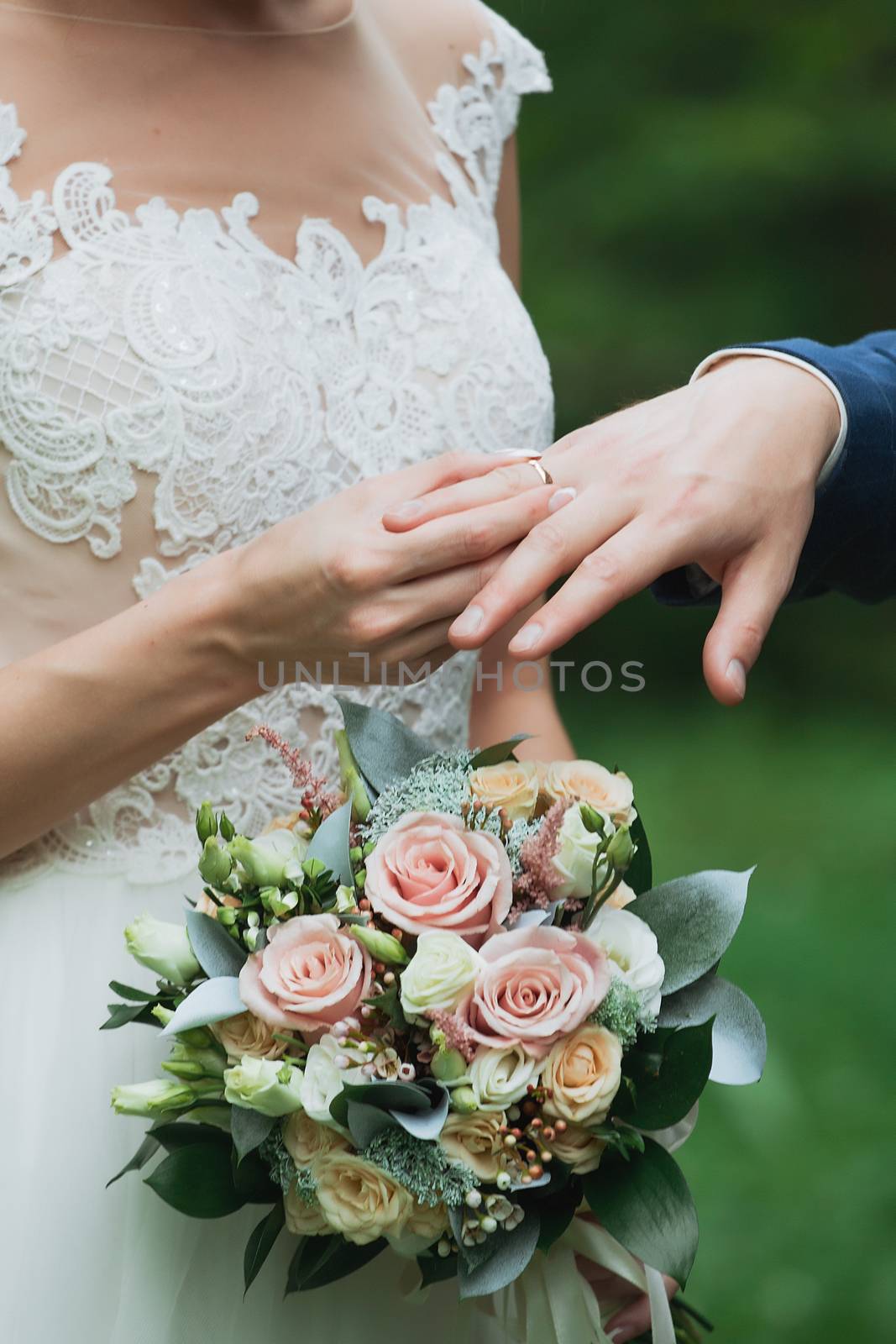 Wedding day. The groom places the ring on the bride's hand.