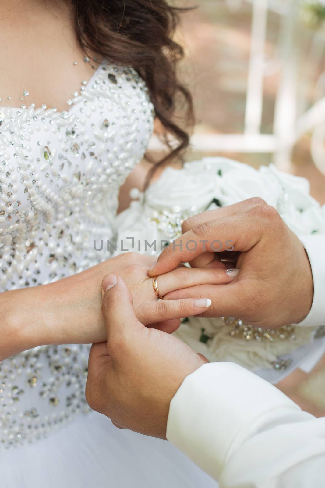 The groom places the ring on the bride's hand. Photo closeup by 3KStudio