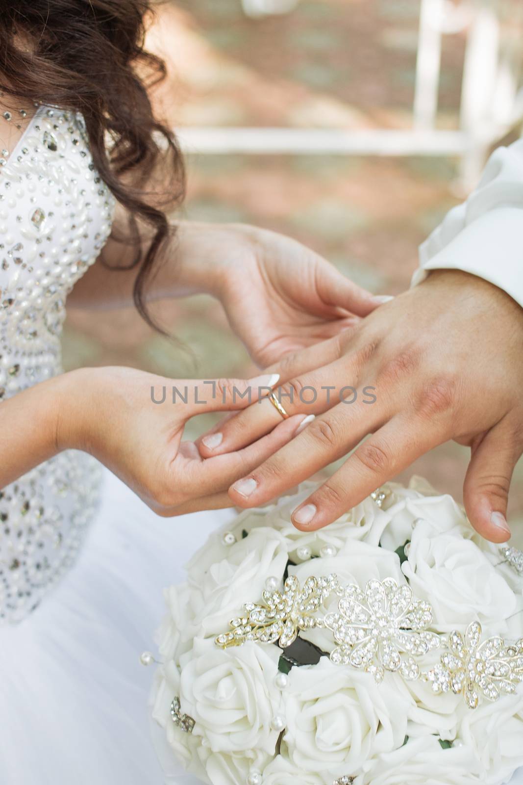 Wedding day. The groom places the ring on the bride's hand.