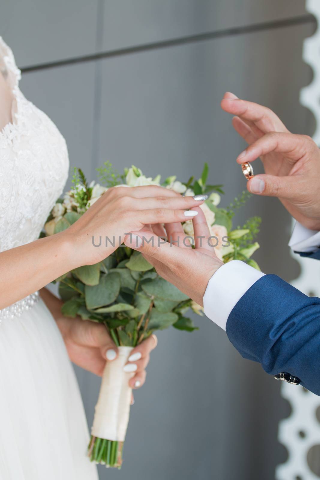 The groom places the ring on the bride's hand. Photo closeup by 3KStudio